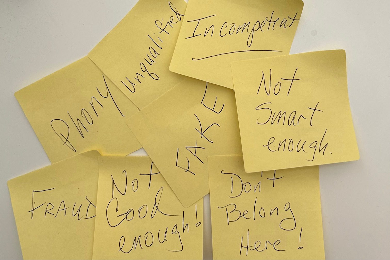 Sticky notes with impostor syndrome thoughts: "Not smart enough," "Fraud," "Phony.