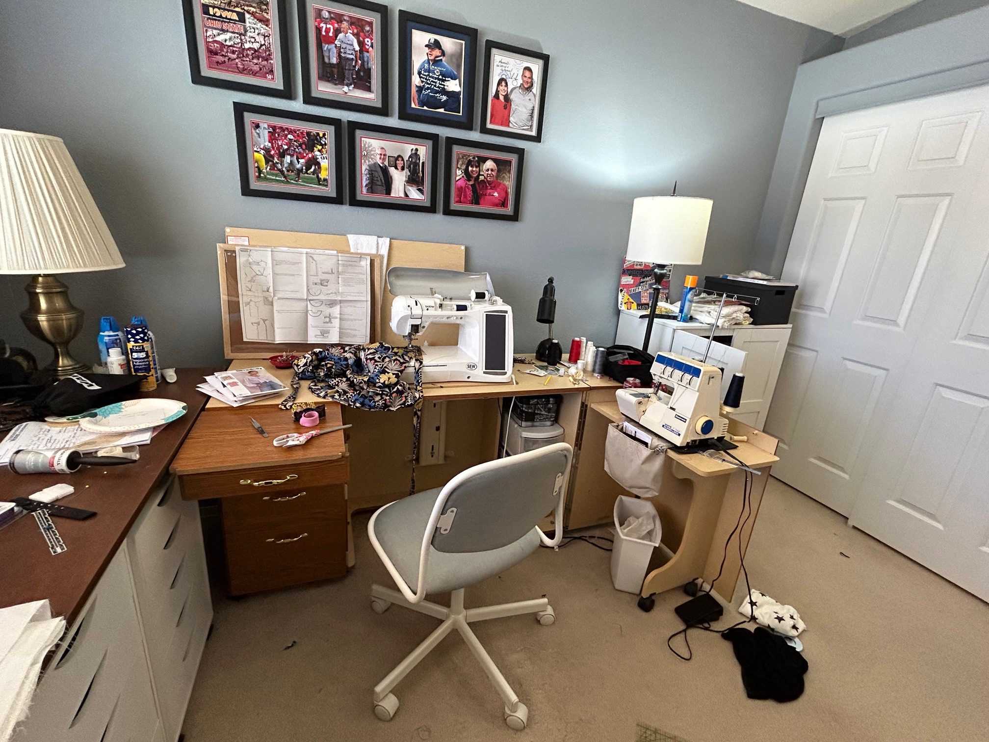 Sewing room with machine, patterns, fabric, and framed photos on the wall.